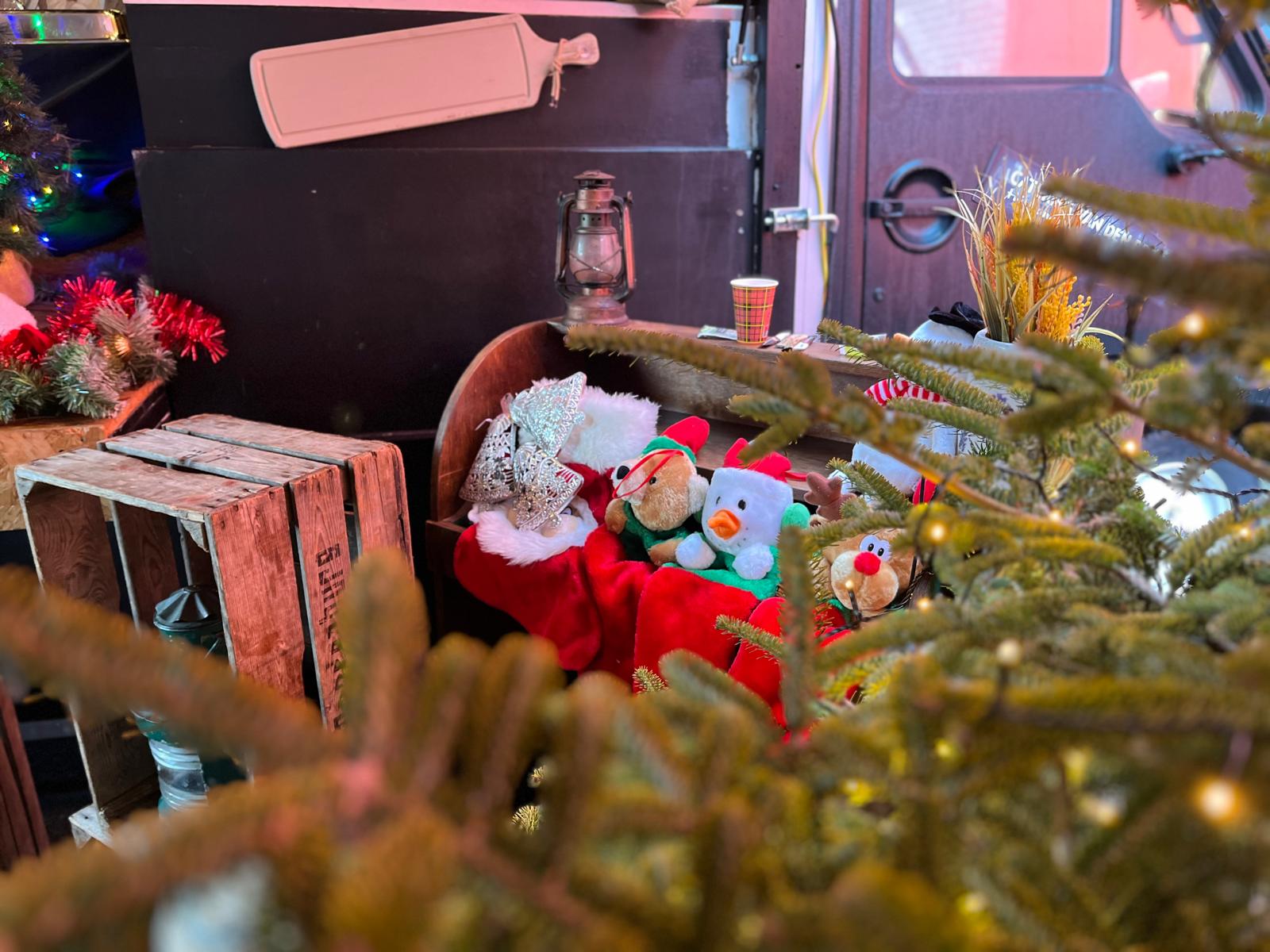 kerstaankleding op een evenement met kerstboom, themaknuffels en kerstsokken