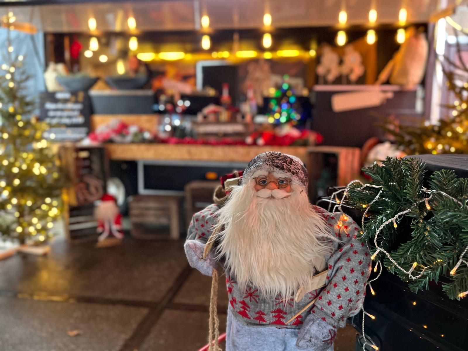 evenement in kerstsfeer met kerstbomen, lichtjes en een kerstman op de voorgrond