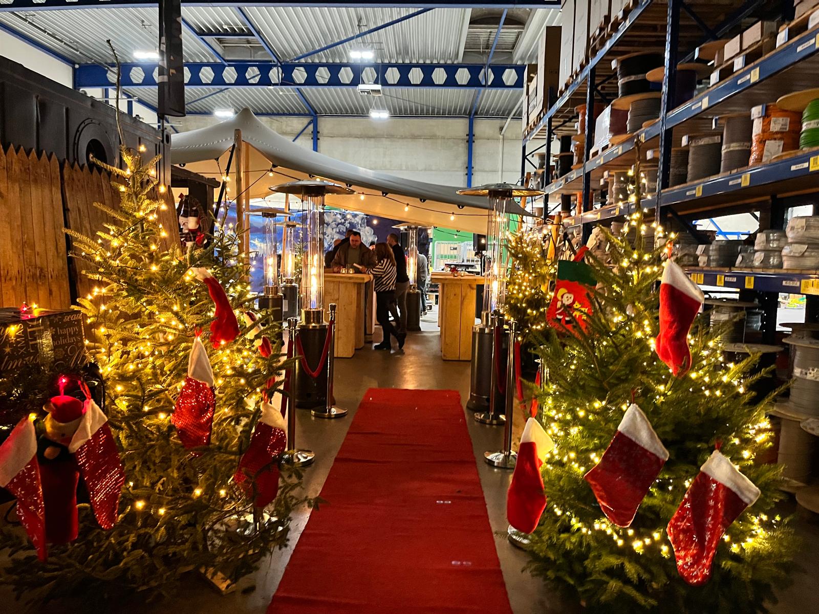 Rode loper op een winters evenement met kerstbomen, lichtjes, borrelende mensen en kerstsokken in de kerstbomen.