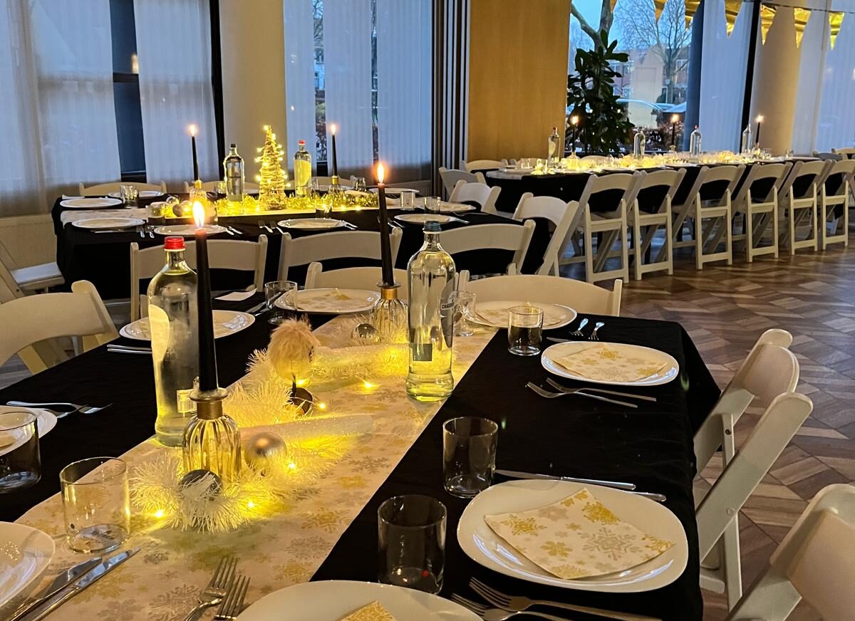 gedekte dinertafel voor een kerstlunch op kantoor. Gezellige tafels met gouden accenten en bijpassende accessoires.