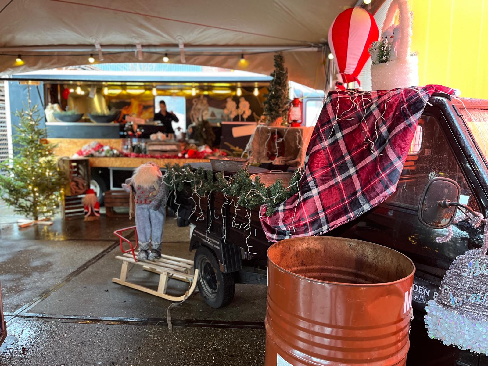 kerstevenement op locatie met bijpassende winterse aankleding, zoals een plaid, kerstman, slee en kerstbomen.